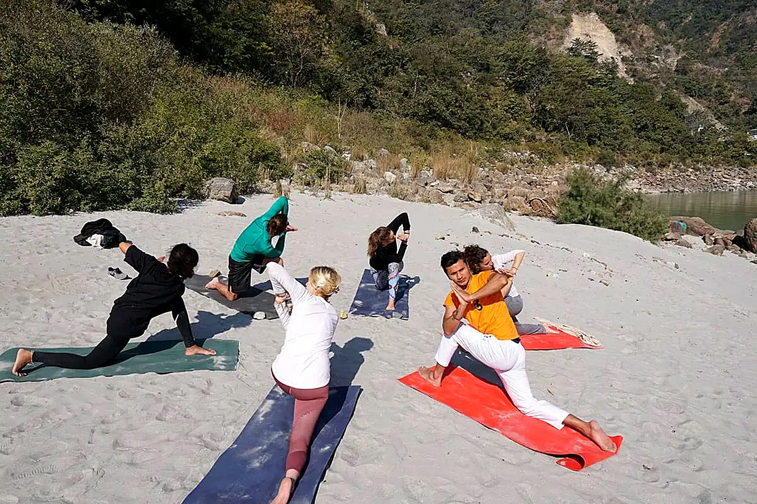 Group yoga class on a sandy riverbank during the Ayurveda retreat