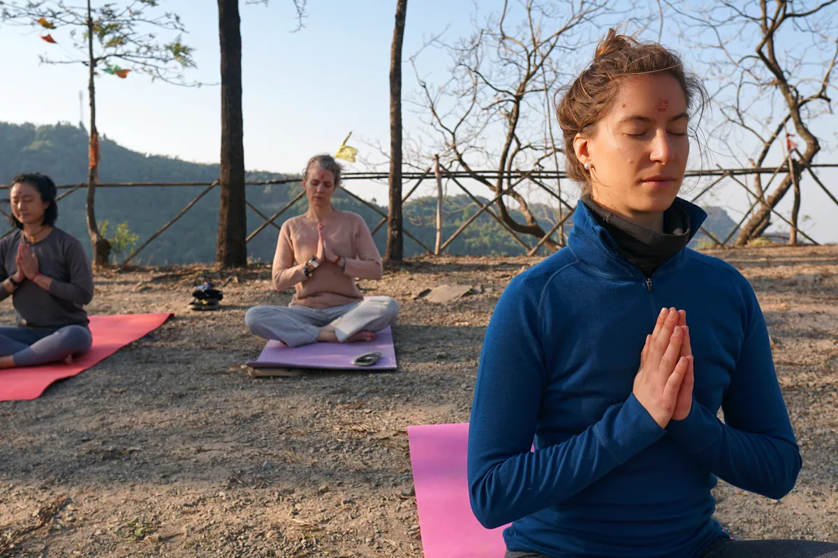 Morning meditation and namaste during an outdoor mantra class