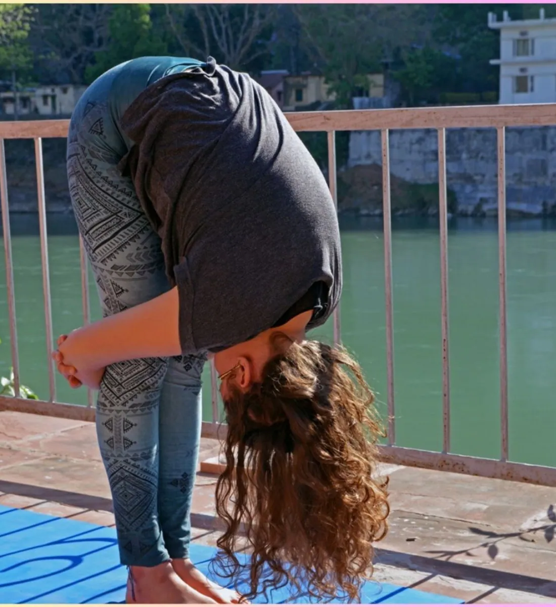 Student in a standing forward fold pose by the riverside