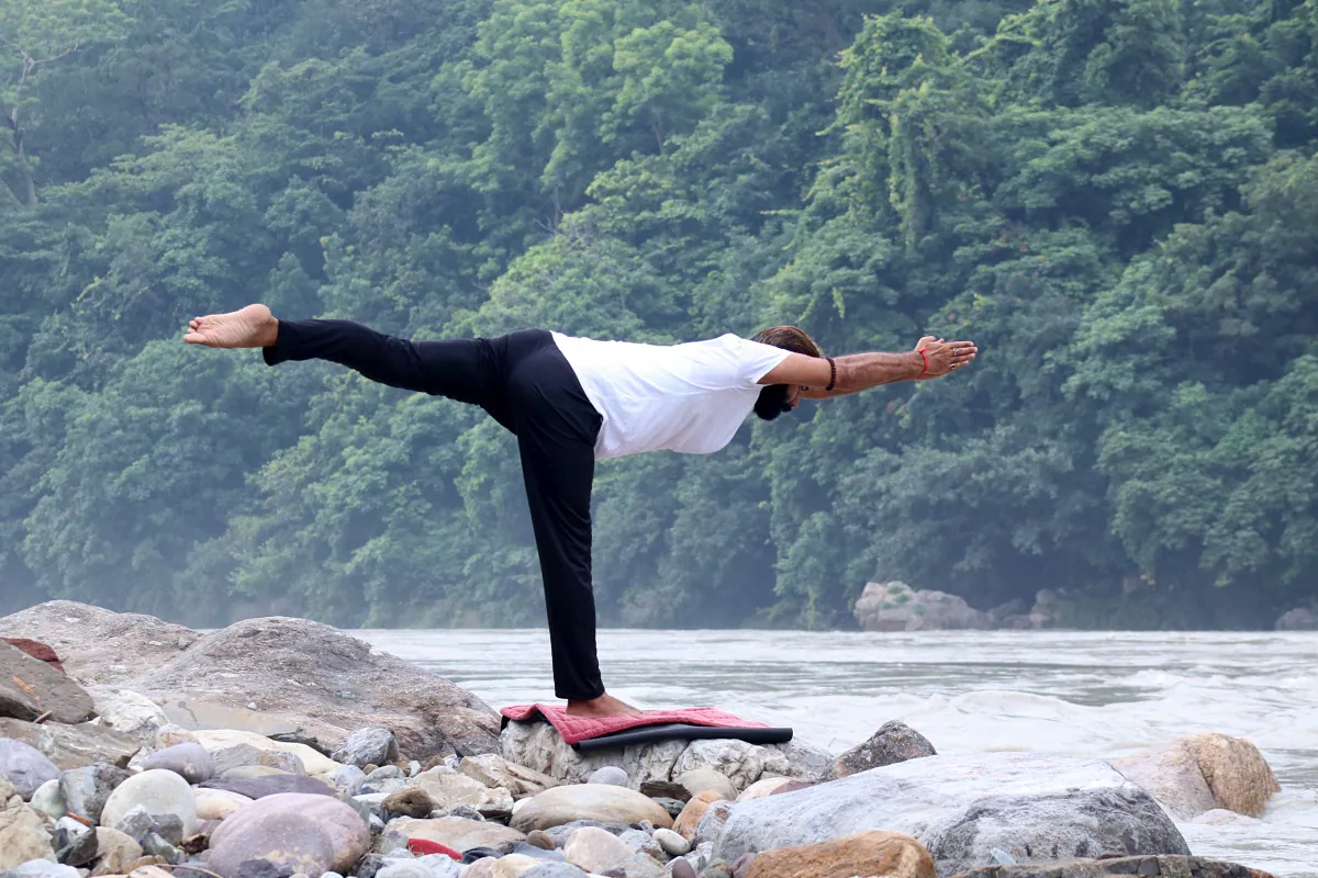 Home yoga practitioner deepening technique by the Ganges in Rishikesh