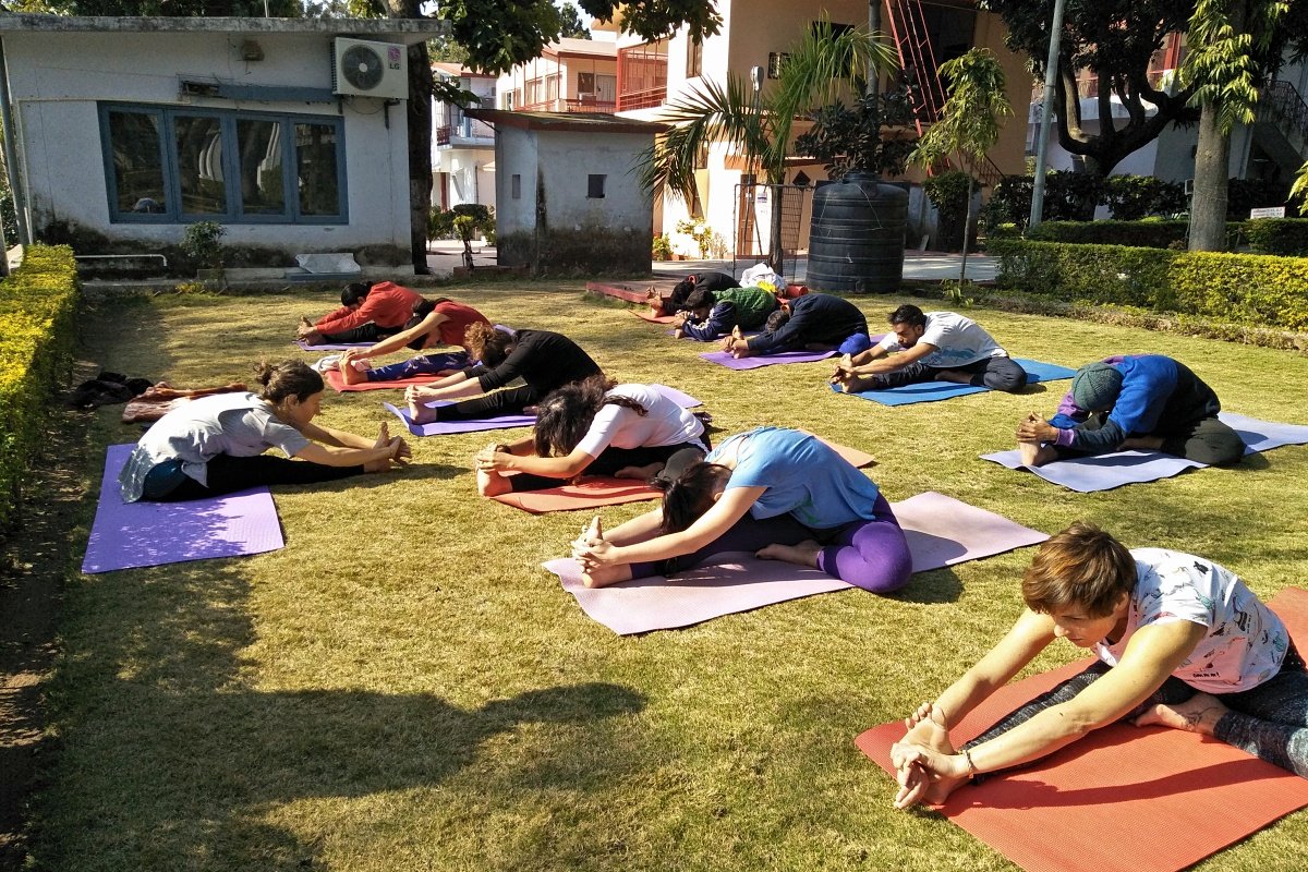 Dedicated beginners receiving hands-on guidance in a group kundalini class in Rishikesh