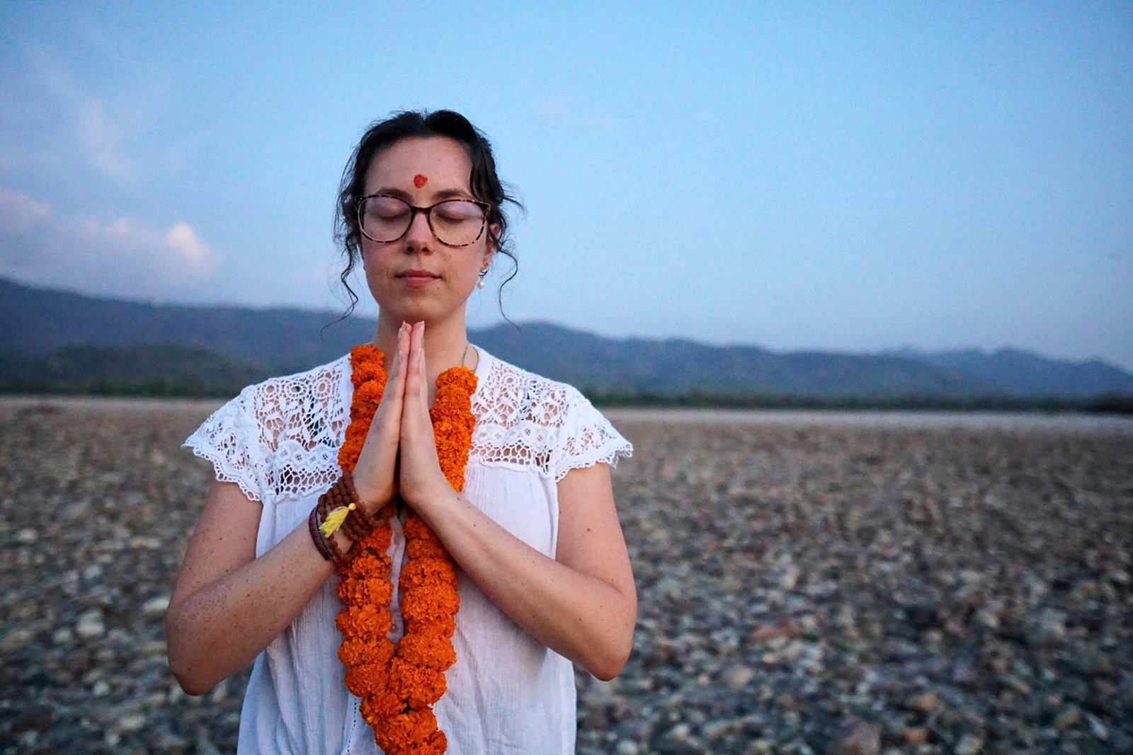 Retreat guests in namaste meditation on the Ganga riverbank in Rishikesh