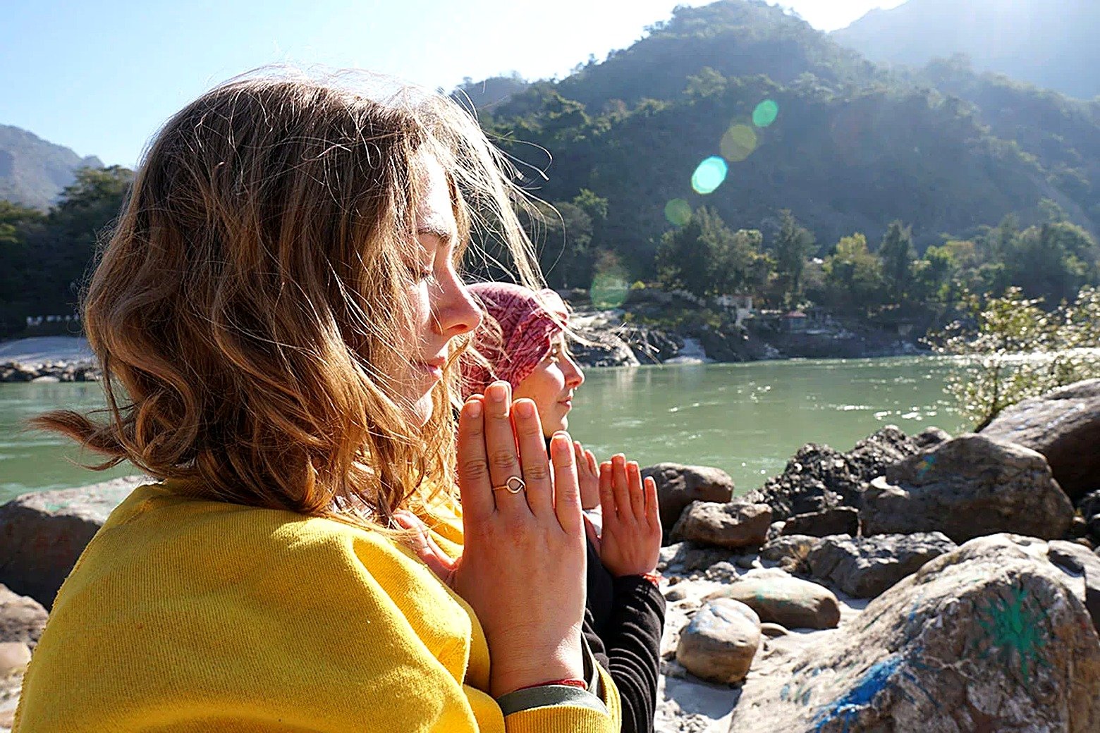 Student in namaste prayer by the Ganga in Rishikesh