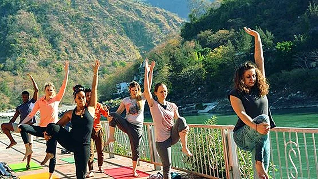 Beginner holding a standing balance pose on a riverside terrace