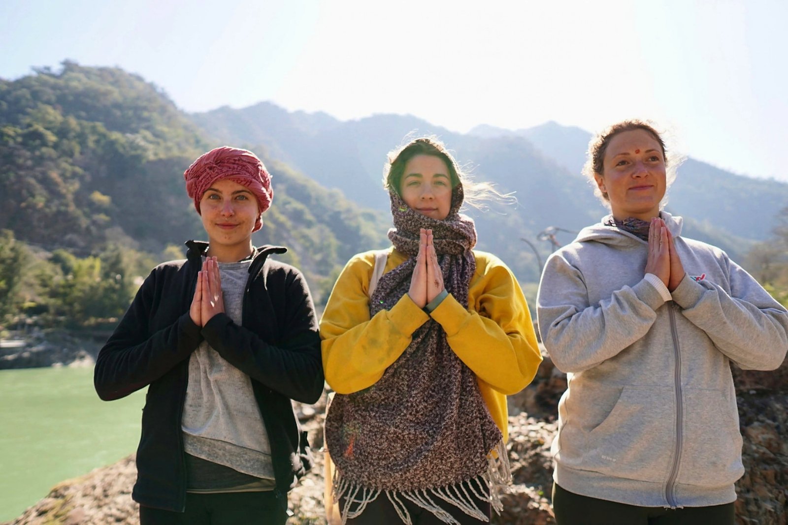 Students chanting mantras in namaste beside the Ganga river