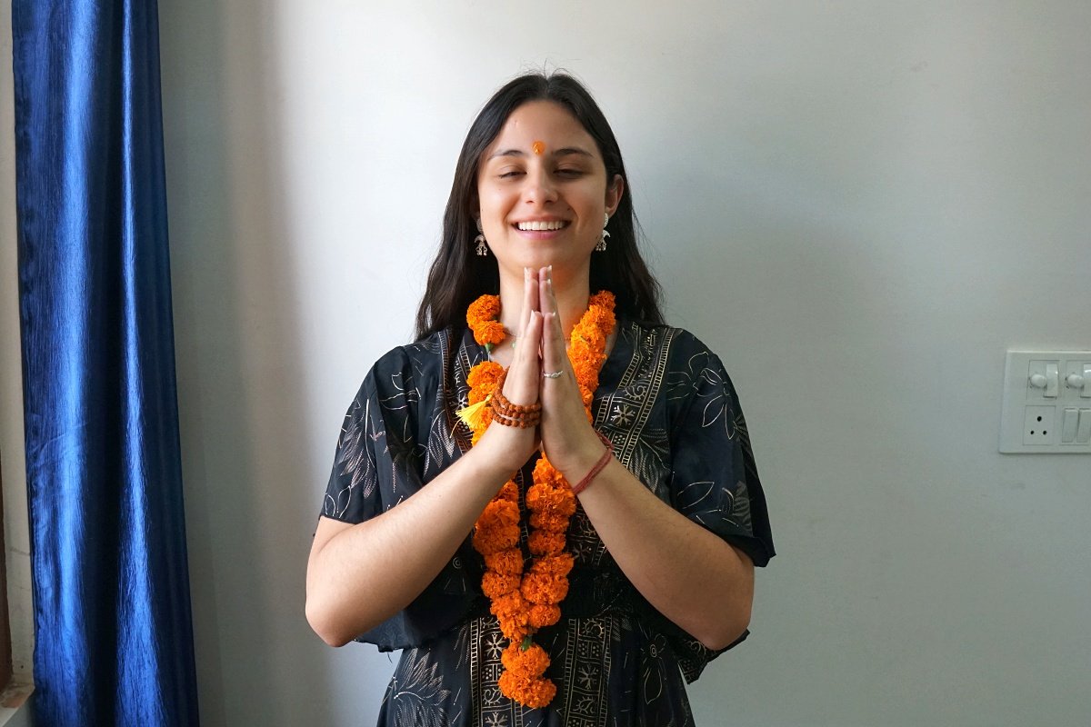 Yoga TTC graduate in namaste with a garland